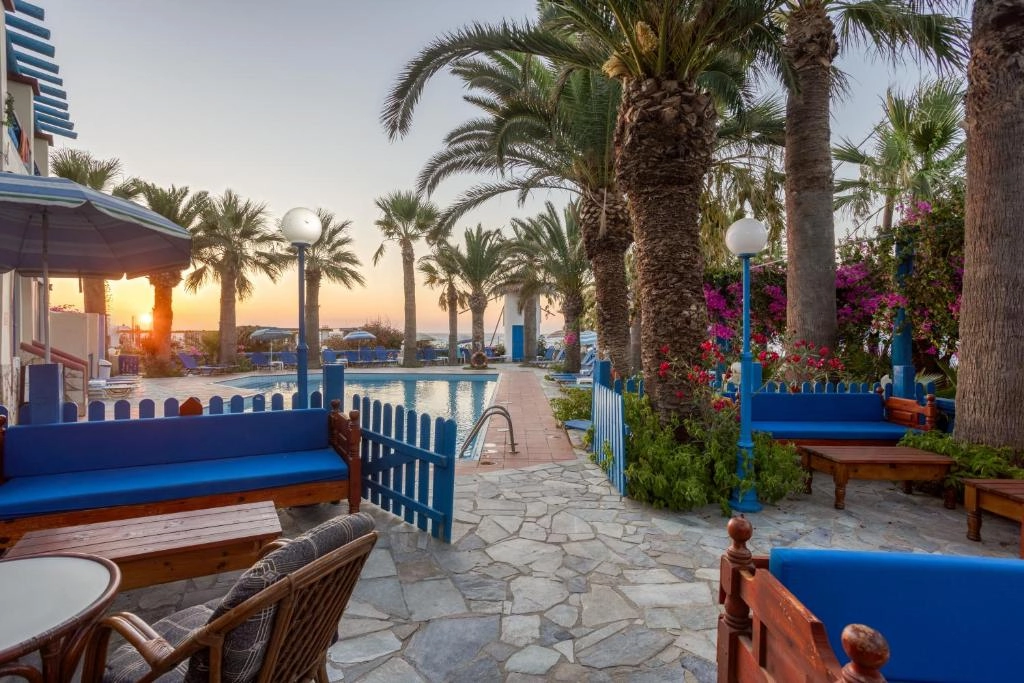 Αυλή Palm Bay με πισίνα, μπλε παγκάκια, φοίνικες και μπουκαμβίλιες